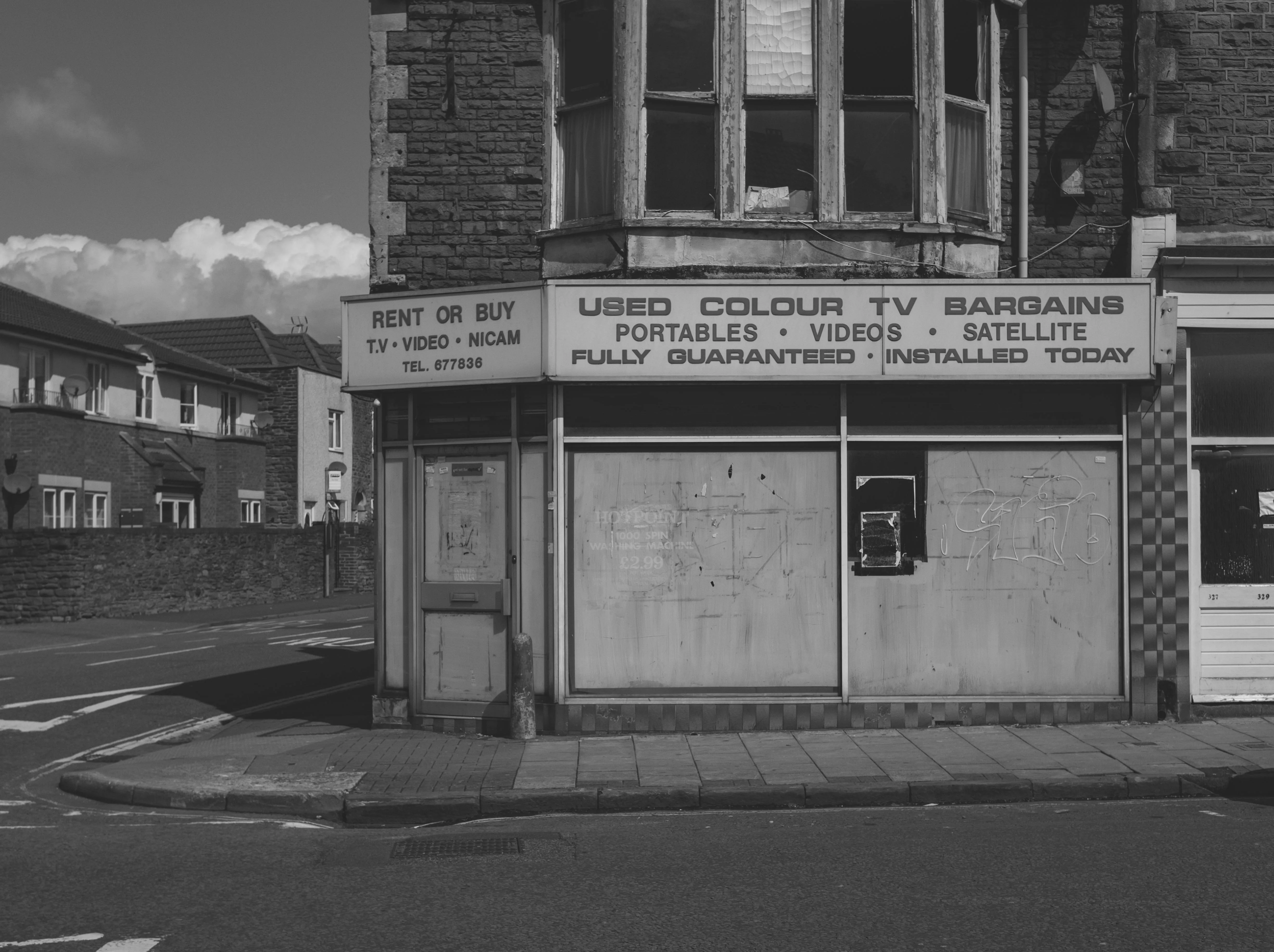 A boarded-up shopfront on a quiet UK street, a business that quietly went under.